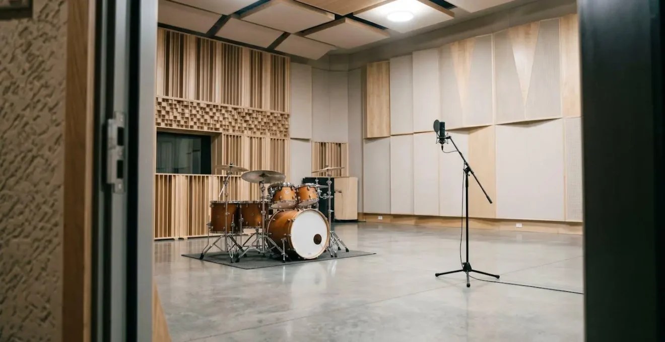 Wide shot of drum kit in spacious recording room with ambient microphone placement capturing natural reverb and room acoustics