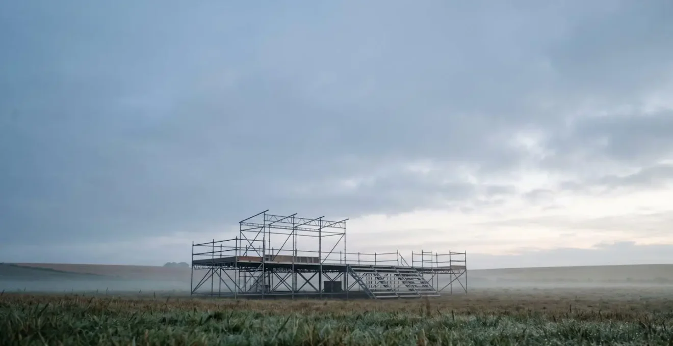 Wide shot of an empty festival stage at dawn with natural lighting and atmospheric negative space conveying anticipation