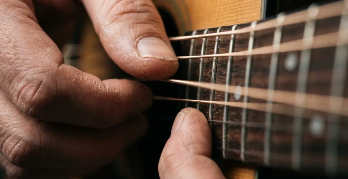 Extreme close-up of guitarist fingers executing intricate fingerpicking pattern on acoustic guitar strings