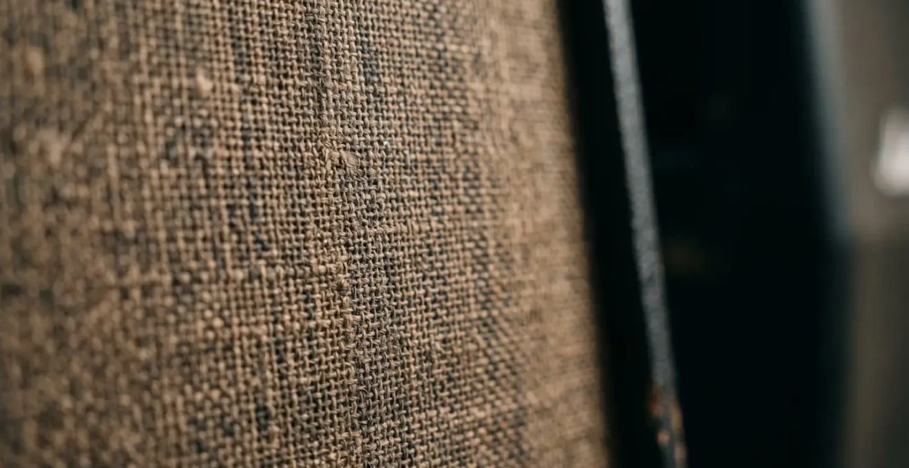 Extreme close-up macro photograph of a guitar amplifier speaker cone showing detailed fabric texture and dust particles with shallow depth of field