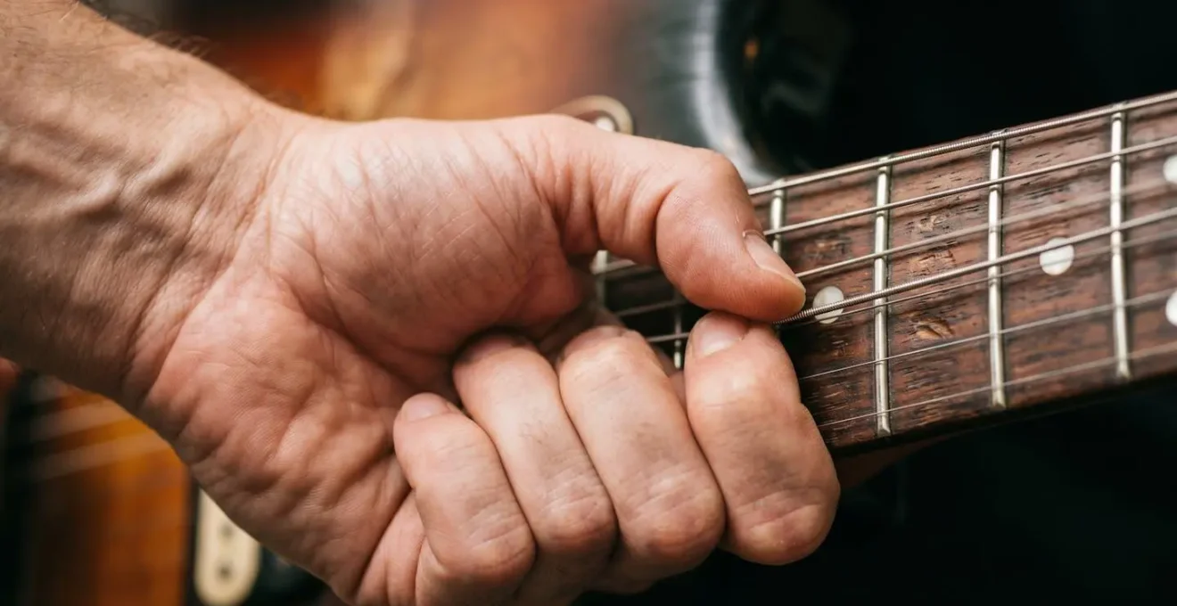 Extreme close-up of guitarist's wrist and fingers demonstrating vibrato technique on guitar strings