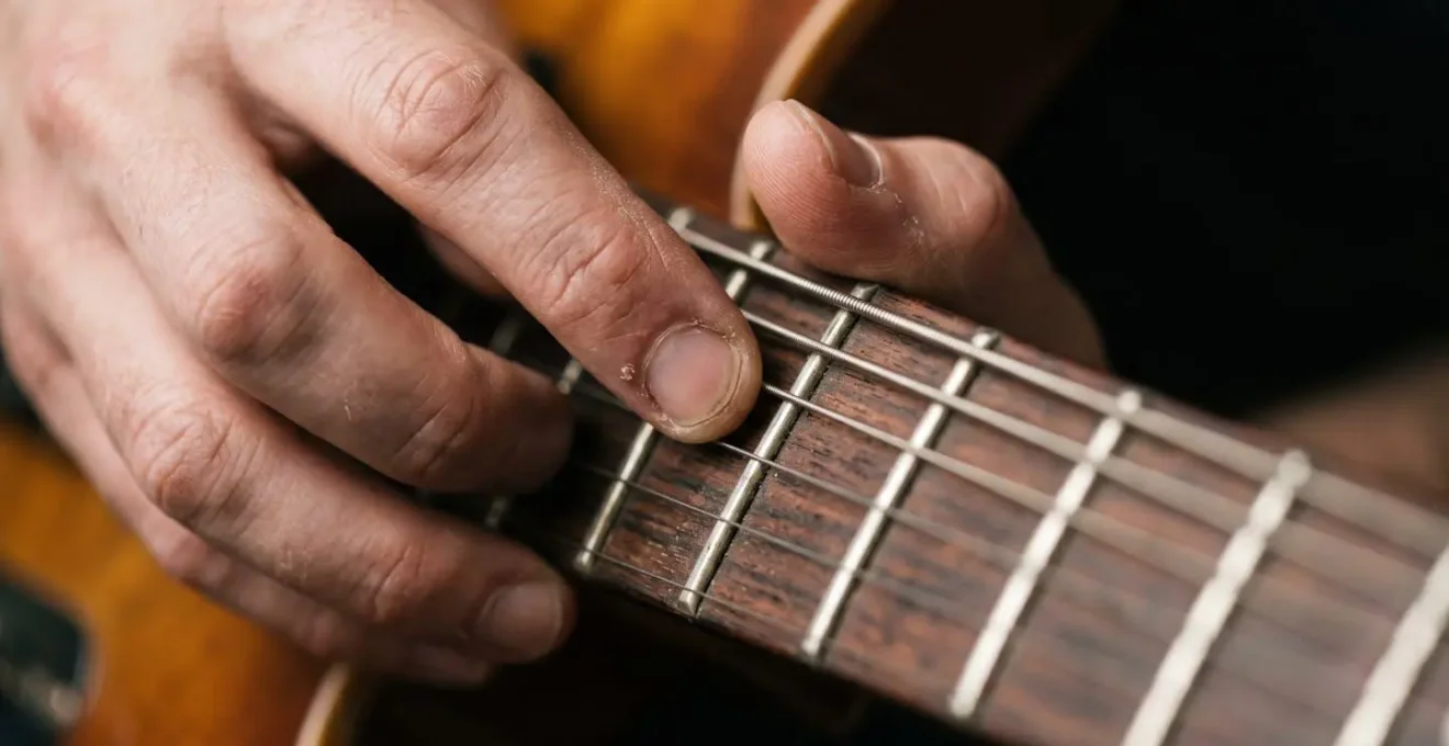 Extreme macro detail of guitarist's fingers executing hammer-on pull-off trill technique on electric guitar fretboard
