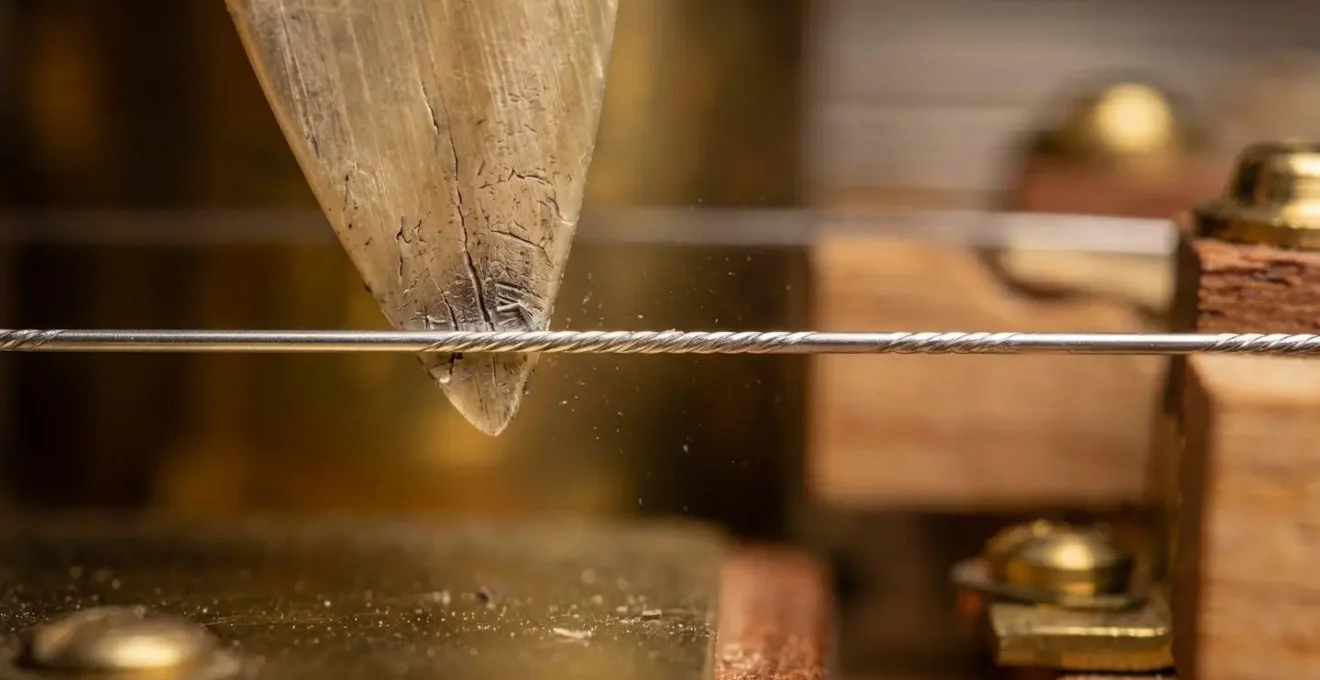 Detailed macro view of harpsichord jack mechanism showing plectrum contact point with string demonstrating tuning sensitivity