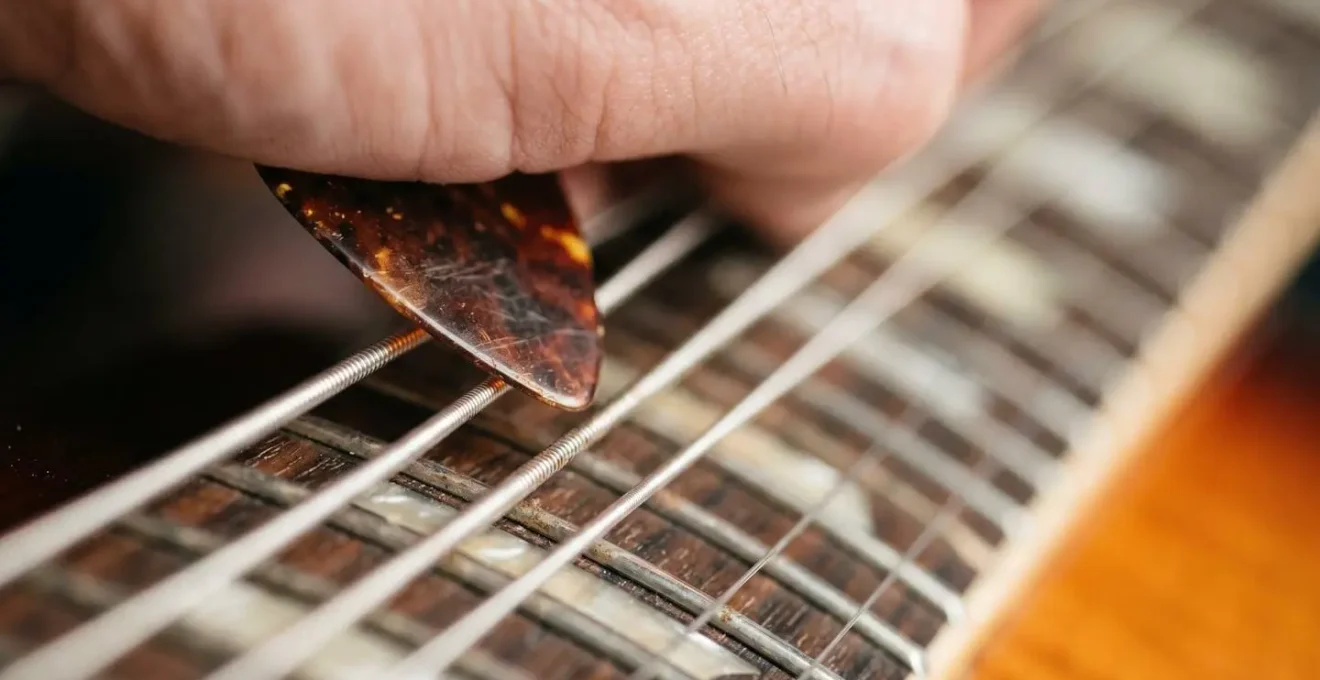 Macro shot of a guitar pick striking palm-muted strings, creating a percussive rhythm with extreme detail on the string texture.