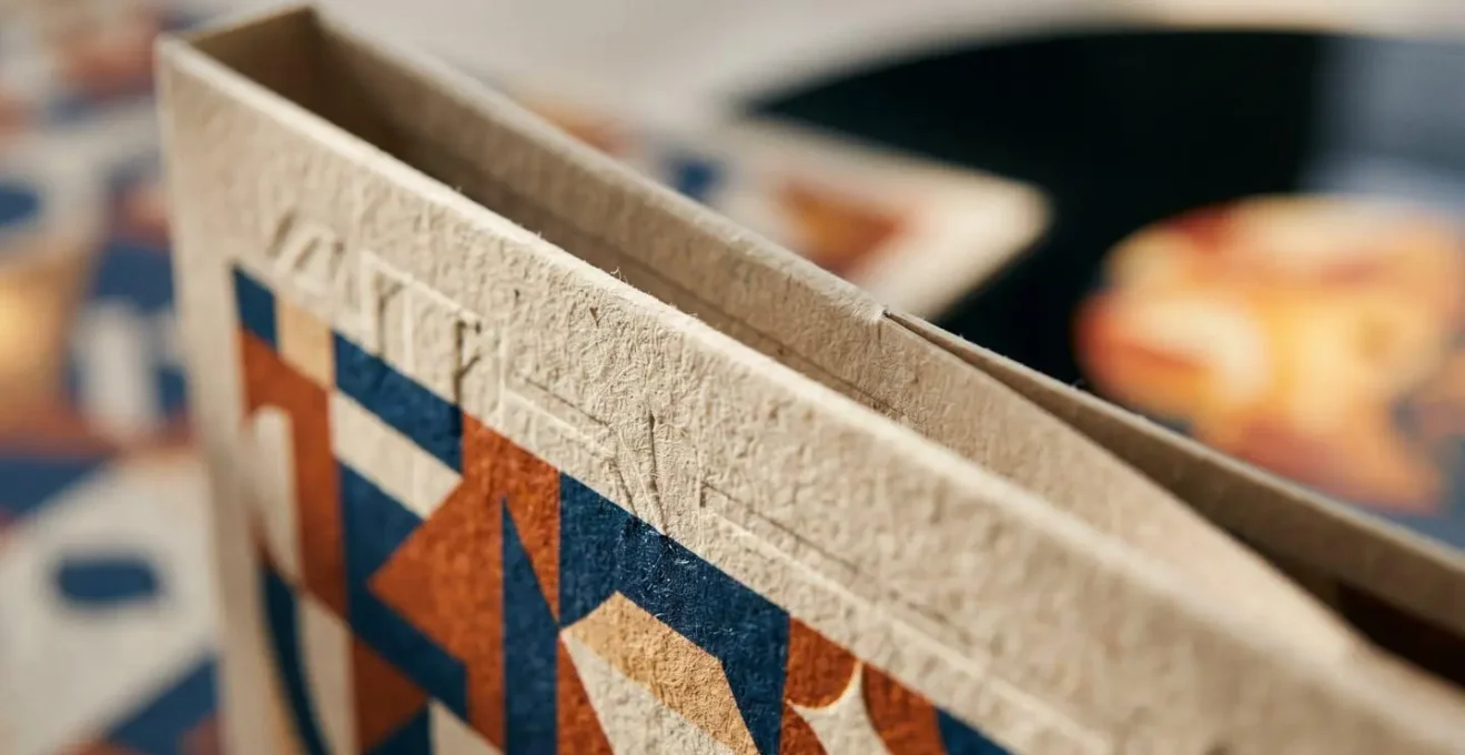 Extreme close-up of vinyl record gatefold packaging showing textured paper surface and embossed details in natural light