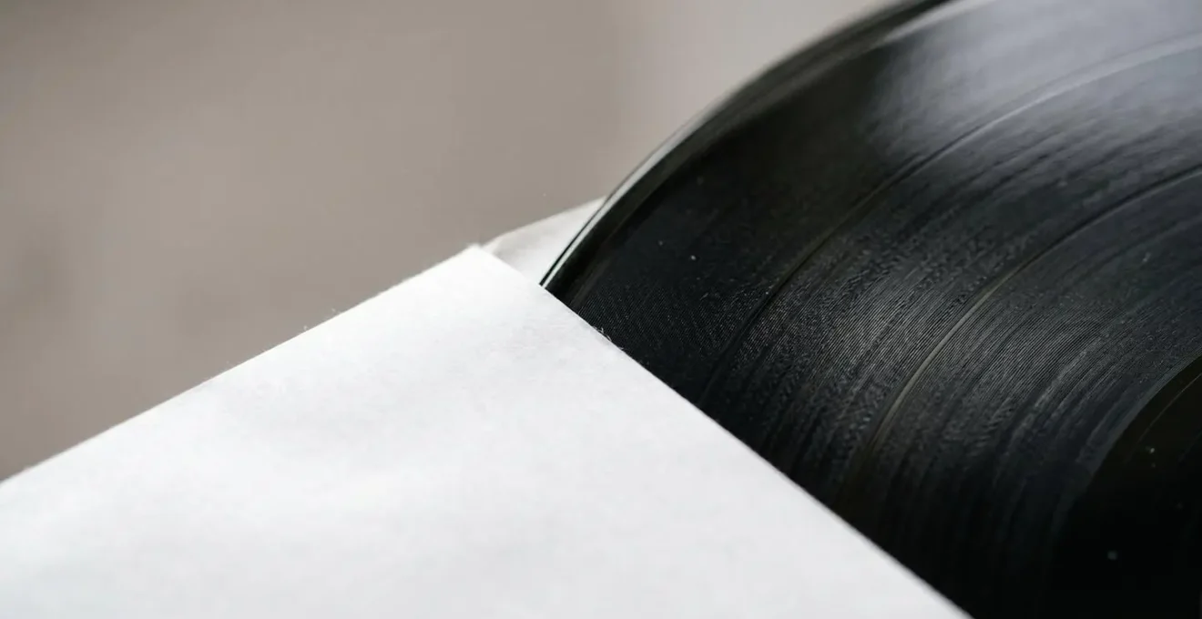 Macro detail of a vinyl record emerging from a pristine anti-static inner sleeve with soft textural focus